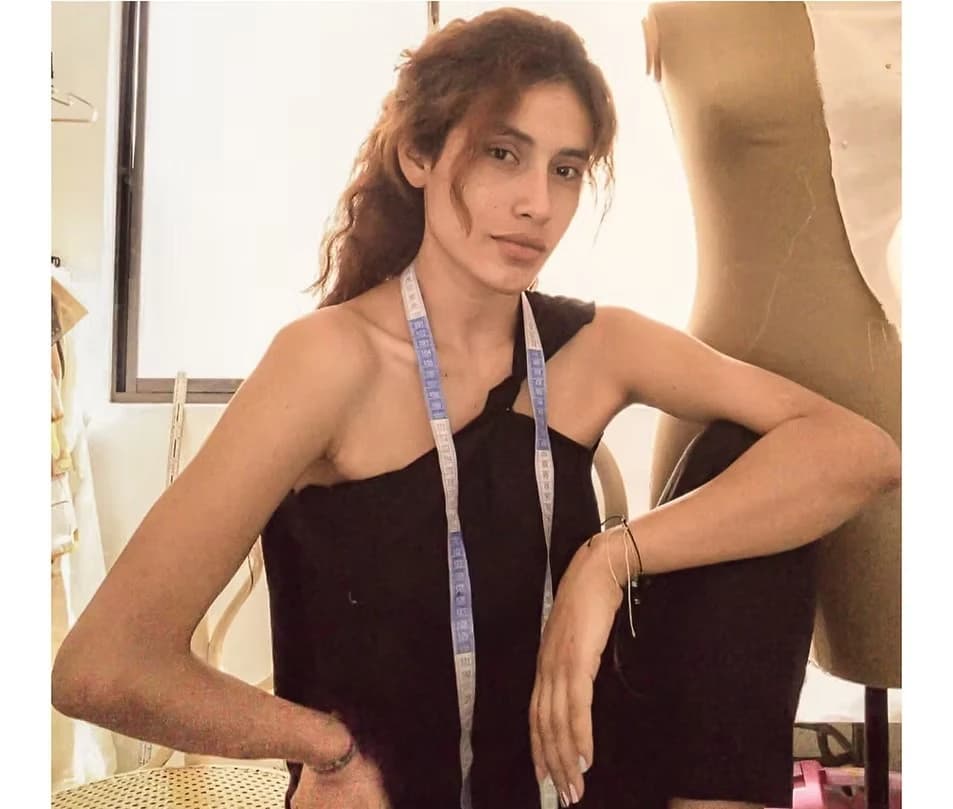 Diseñadora con la cinta métrica al cuello, apoyada junto a un maniquí en el taller