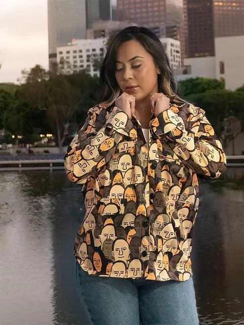 Modelo con la camisa de rostros en café y mostaza junto a un espejo de agua